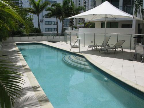 a large swimming pool with chairs and an umbrella at Cilento Mooloolaba in Mooloolaba