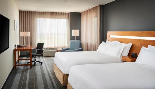 a hotel room with two beds and a desk at Novotel Toronto Vaughan Centre in Vaughan