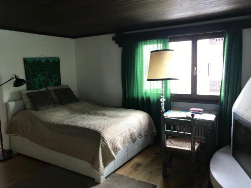 a bedroom with a bed with green curtains and a window at TOP LOCATION - Klosters center - 130m distance to ski lift Parsenn Gotschnabahn and railway station Klosters Platz - direct connection to Davos in Klosters