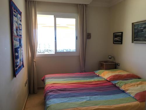 ポリス・デ・アボナにあるLeuchtturmterrasseのカラフルなベッドと窓が備わるベッドルーム1室が備わります。