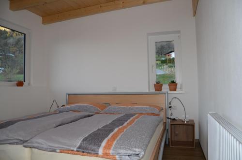 a bed in a white bedroom with a window at Appartement Christiane in Bludenz
