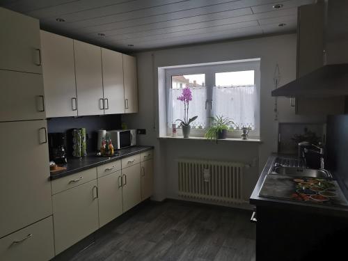 una cucina con armadi bianchi, finestra e lavandino di Ferienhaus CasaNoWa a Kaufbeuren
