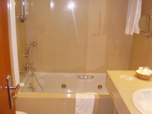 a bathroom with a bath tub and a sink at Hotel Central Parque in Maia