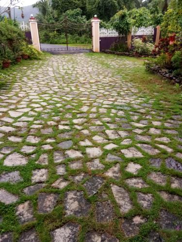 a cobblestone walkway in a yard with grass at THE ENCHANTING NEST in Borim