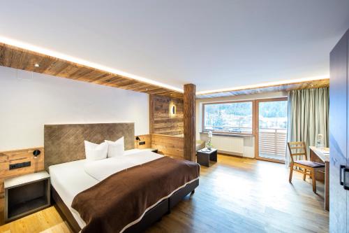 a bedroom with a bed and a desk and a window at Posthotel Pfunds in Pfunds