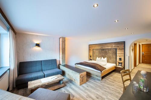 a hotel room with a bed and a blue couch at Posthotel Pfunds in Pfunds