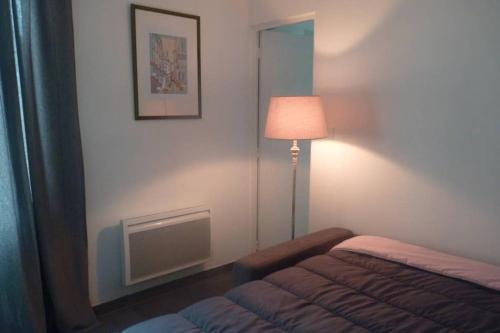 um pequeno quarto com uma cama e um candeeiro em L'Oseraie em Moisenay
