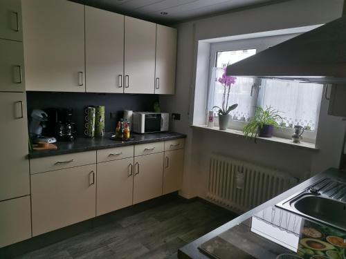 cocina con armarios blancos, fregadero y ventana en Ferienhaus CasaNoWa en Kaufbeuren