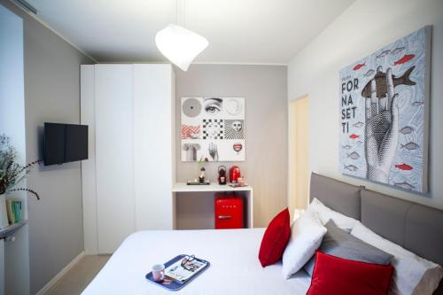 1 dormitorio con cama blanca y almohadas rojas en Kramer House, in the fashion district!, en Milán