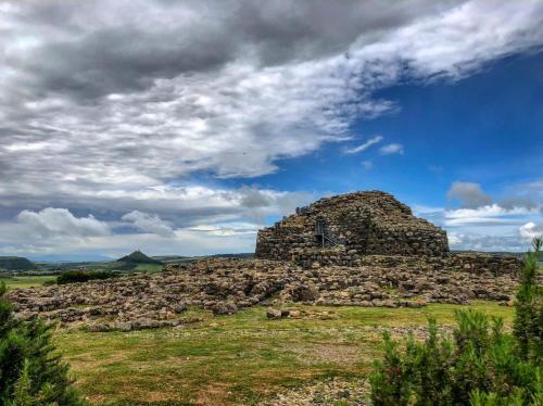 an old stone building in a field under a cloudy sky at Casa Susanna Rural Sardinia in Sini