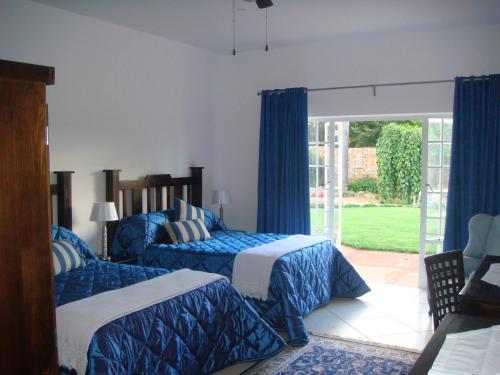 Un dormitorio con dos camas con sábanas azules y blancas. en Heatherdale Guesthouse & Shuttle Services, en Pretoria