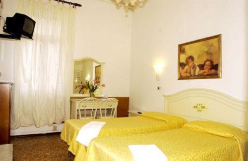 Habitación de hotel con 2 camas con sábanas amarillas en Hotel Airone en Venecia