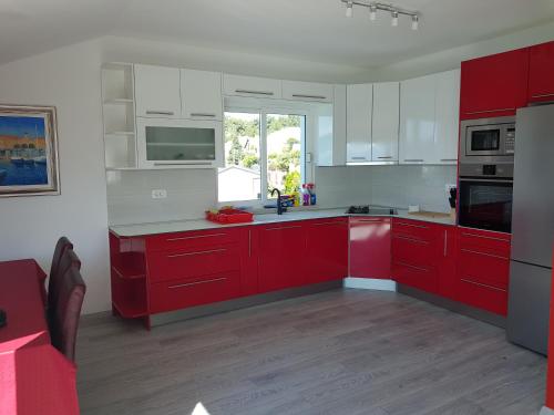 a red kitchen with white cabinets and a window at Apartments Kocak in Blace