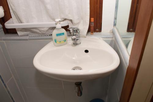 a bathroom sink with a bottle of soap on it at Le Stelline B&B in Fiumicino