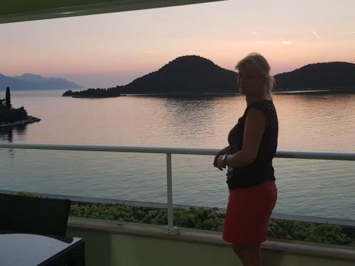 a woman standing on a balcony looking out at the water at Apartments Kocak in Blace
