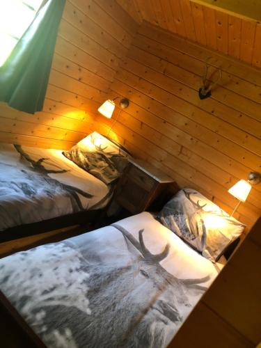 a room with two beds with a deer on the sheets at Sfeervolle Blokhut in Oostvoorne