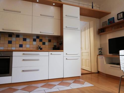 a kitchen with white cabinets and a tv at Dimora Apartments with free parking in Ljubljana