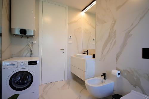 ein Badezimmer mit einer Waschmaschine und einem Waschbecken in der Unterkunft New apartment with swimming pool near the beach in Ičići