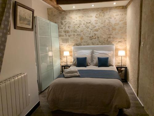 a bedroom with a large bed with two blue pillows at Le Petit Hameau de Chantilly - Studio Chic et Charme au Coeur de Chantilly - Classé 3 étoiles in Chantilly