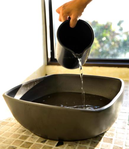a person pouring water from a funnel into a bowl at Coco de Mer Hotel and Black Parrot Suites in Grand'Anse Praslin