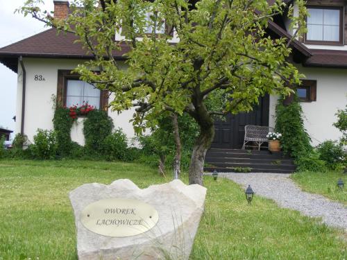una casa con un árbol y un cartel en el patio en Dworek Lachowicze, en Grzegorzewice