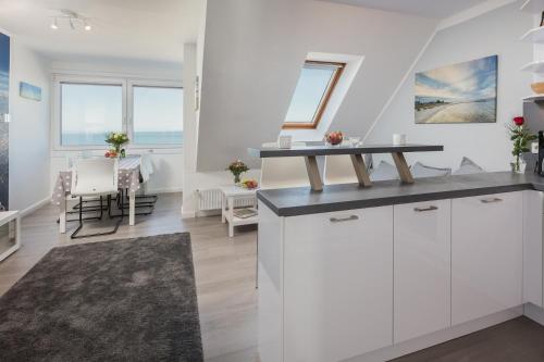 a kitchen with white cabinets and a dining room with a table at Traum Ostseemeerblick in Schönberger Strand