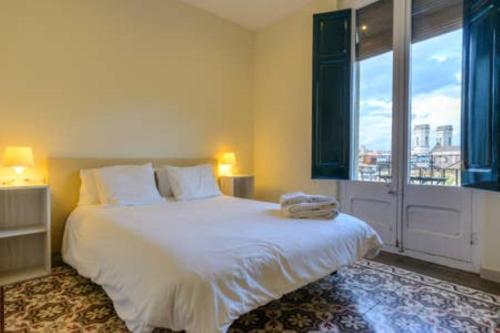 a bedroom with a large white bed and a window at Apartamento Les Pedreres in Girona