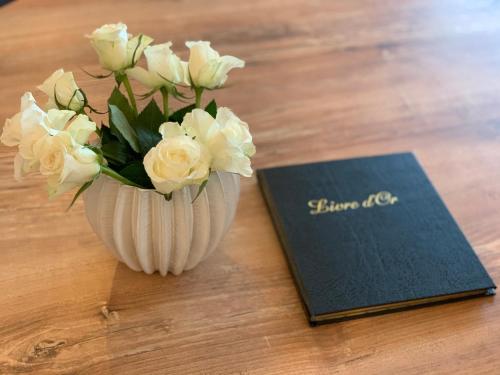 a vase of white flowers next to a book at L' Évéa Garden in Le Relecq-Kerhuon