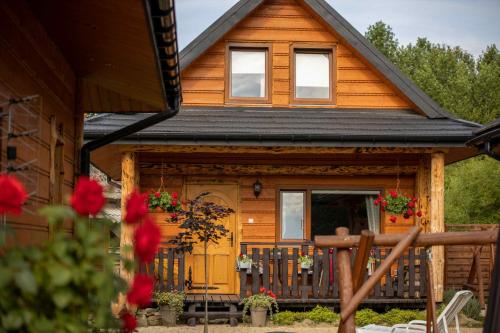 ein Holzhaus mit einer Veranda mit Blumen darauf in der Unterkunft Chaty Anety Domki Całoroczne in Solina