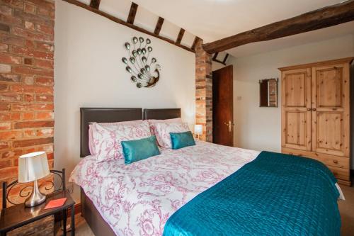 a bedroom with a large bed with blue pillows at Landews Meadow Cottages in Badlesmere