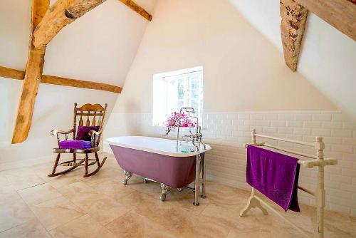 a large bathroom with a purple tub and a chair at Swafield Hall in Swafield