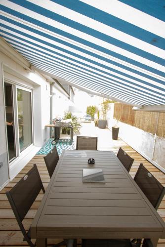 - une table et des chaises en bois sur une terrasse avec un auvent dans l'établissement Les Aigrettes - Appartement spacieux - Terrasse et garage, à Concarneau