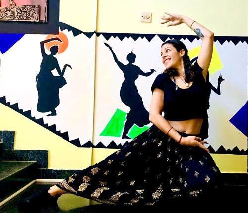 een vrouw in een zwarte jurk dansend voor een muur bij Indian Art Villa in Varkala