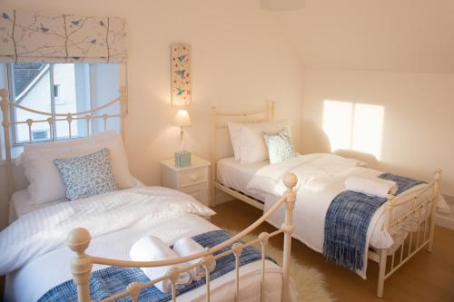 a bedroom with two beds and a window at The Corner Cottage in Sandwick