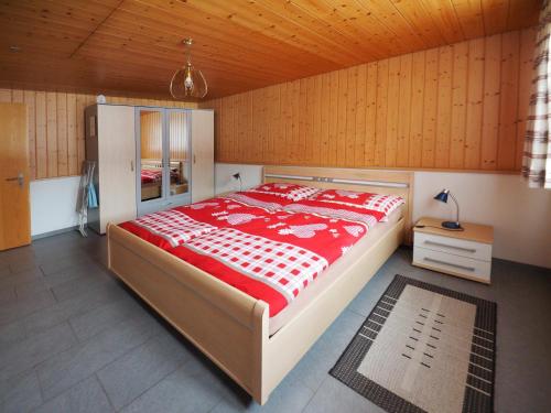 ein Schlafzimmer mit einem großen Bett mit einer roten und weißen Tagesdecke in der Unterkunft Holidayapartment Sydach in Wilderswil