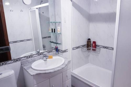 biała łazienka z umywalką i prysznicem w obiekcie Apartamento completo con parking privado y WiFi en San Roque w mieście Vigo