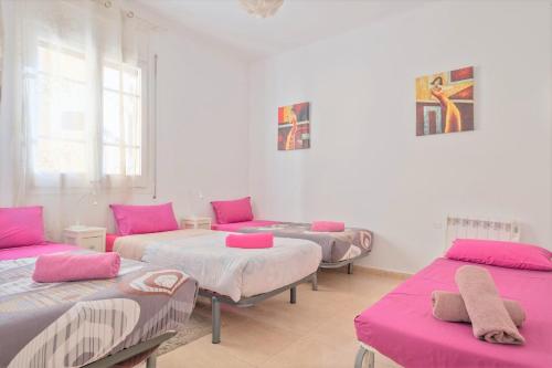 Habitación con 3 camas y almohadas rosas. en Apartamentos Tarradellas Sants Estació, en Barcelona
