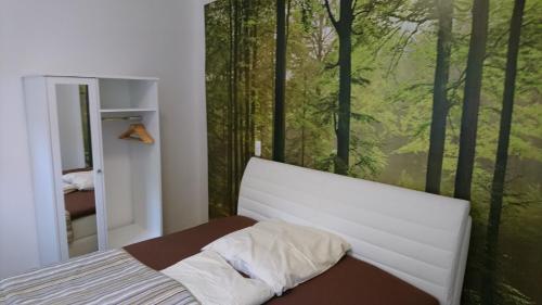 Schlafzimmer mit einem Bett und einem großen Fenster mit Bäumen in der Unterkunft Ferienwohnung Weseraue in Holzminden