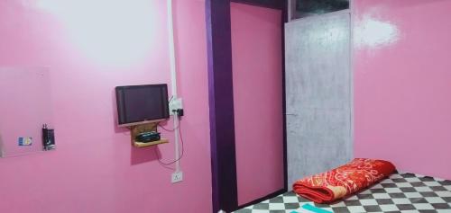 a room with a pink wall with a tv and a pillow at Shalom guest house in Cherrapunji