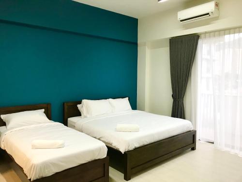 Duas camas num quarto com uma parede azul em By The Beach - Luxury 2 Bedrooms Family Suite em Batu Ferringhi