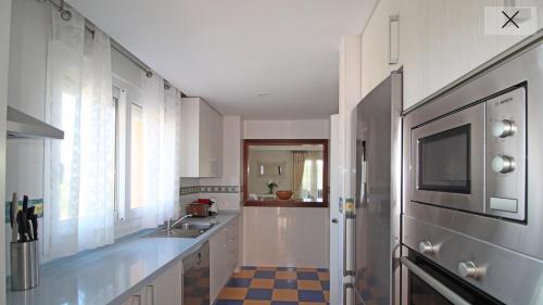 a white kitchen with a sink and a microwave at Marbella Deluxe Rooms in Royal Cabopino Townhouse in Marbella
