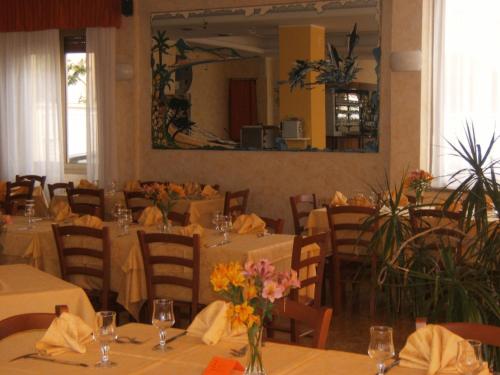 un restaurante con mesas y sillas con flores. en Hotel Delfino, en Laigueglia