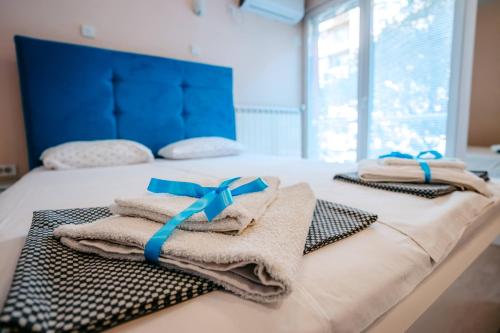 two towels on a bed with blue bows on them at Turist Apartment in Niš