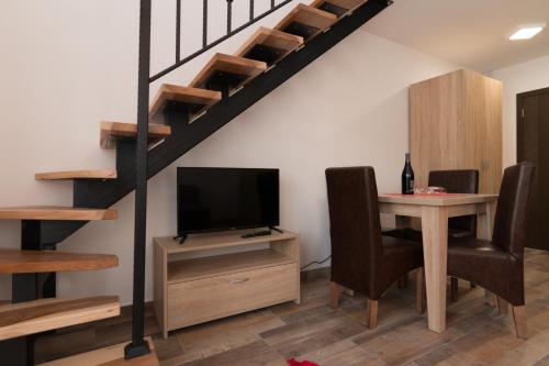 a living room with a table and a tv and a staircase at Apartmani Tarski Vuk in Kaludjerske Bare