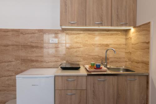 a kitchen with wooden cabinets and a sink at Apartmani Tarski Vuk in Kaludjerske Bare