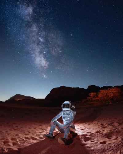 a person in a spacesuit sitting in the desert at night at RUM STARDUST lUXURY CAMP in Wadi Rum
