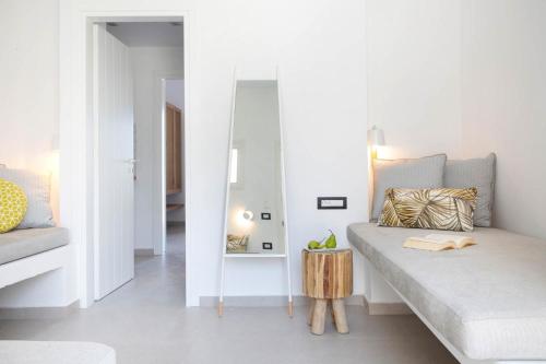 a white living room with a couch and a mirror at Kouros Village in Antiparos Town