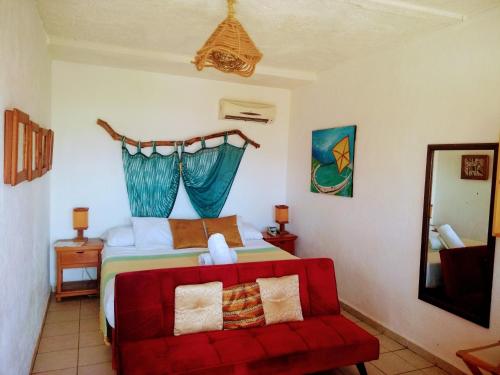 a bedroom with a bed and a red couch at Hotel Gilda in Coyuca