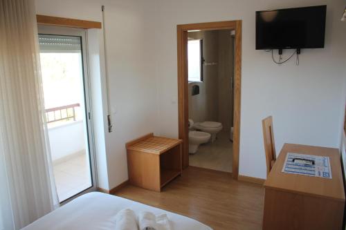 a bedroom with a bed and a bathroom with a toilet at Hotel Solar da Charneca in Leiria