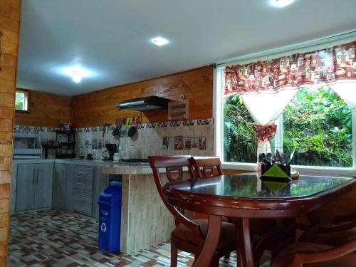 a kitchen with a table and chairs and a window at Cabaña de descanso arcoiris del lago 3 in Pasto